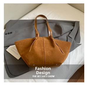 Détail du cabas en daim marron avec poignées en cuir et clous métalliques de fond