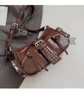 Close-up of brown leather moto bag featuring silver zippers, rivets and metallic buckles