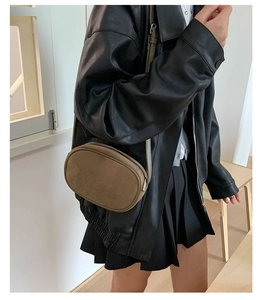 Detailed close-up of dark brown suede cross-body bag worn by a model in a minimalist style