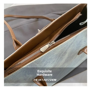 Macro shot of silver metal zipper and brown leather trim on light blue denim tote bag