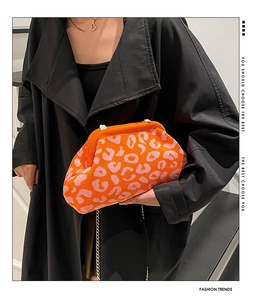 Gros plan du sac nuage orange à motif léopard en tricot avec chaîne sur manteau noir