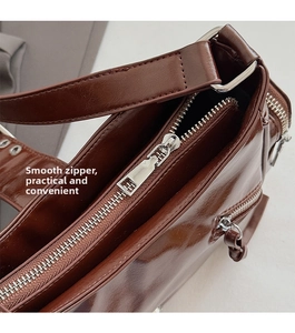 Detail view of the silver metal zipper and dark brown oily leather on the motorcycle bag