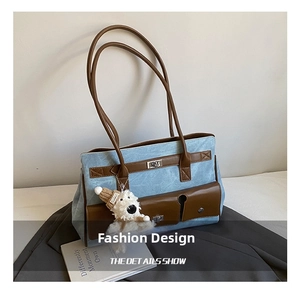 Detail of blue denim tote bag featuring brown leather trim and cute plush bear charm