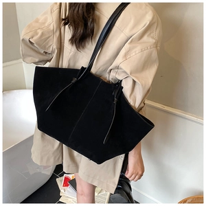 Close-up of black suede tote bag with slim shoulder straps and knotted detail