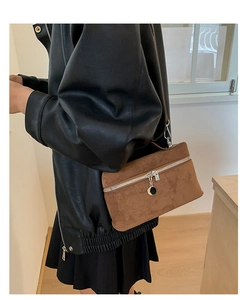 Detail of caramel suede crossbody bag with decorative black and gold metal pendant
