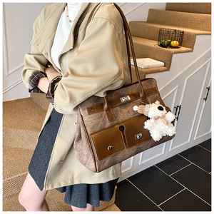 Detail of vintage brown tote bag with metal twist locks and white plush bear charm