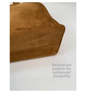 Détail macro du sac fourre-tout en daim marron avec coutures renforcées et texture