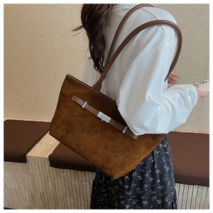 Detail of caramel brown suede tote bag with leather strap and silver buckle on shoulder
