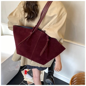 Détail du sac seau bordeaux vintage avec nœud décoratif et texture en daim mat raffiné