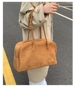 Detalle de un bolso Boston de ante marrón con textura mate y asas largas para hombro