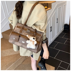 Detail of vintage brown leather tote bag with silver lock pocket and bear charm on model