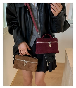 Detail view of suede mini bags in burgundy and brown with silver ring zipper and pendant