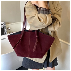 Detail of burgundy suede tote bag showing thin leather straps and tie knot design