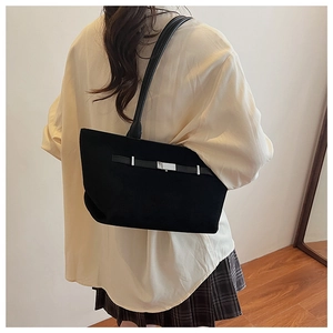 Dettaglio della borsa tote in camoscio nero con fibbie argentate e tracolla in pelle