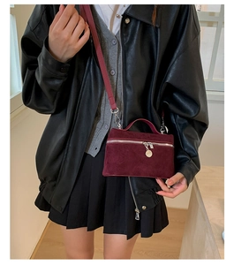Detail of burgundy vanity bag with silver hardware and pendant on a leather jacket outfit