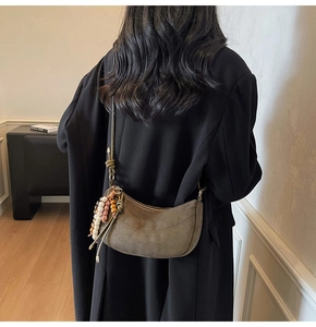 Detail of olive brown suede half-moon bag with ethnic beaded tassel and slim strap