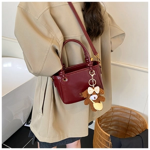 Détail du sac seau bordeaux brillant avec charmant petit ours en peluche marron