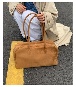 Bolso Boston de ante marrón con cremallera plateada y asas dobles en escena de exterior