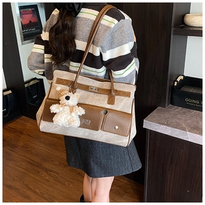 Close-up of canvas tote bag featuring leather flap pocket, metal lock and bear charm