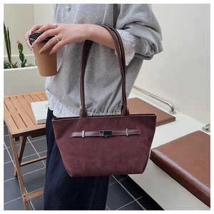 Detail of burgundy suede tote bag featuring decorative silver metal eyelets and straps