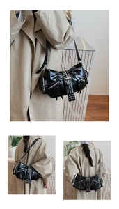 Close-up of black patent leather underarm bag with silver zippers and punk studs