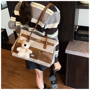 Detail of canvas tote bag with brown leather trim and cute white plush bear pendant
