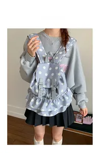 Detail of light blue polka dot backpack with ruffle hem and buckle closure on model
