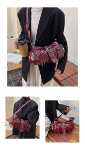 Detail of burgundy glossy faux leather biker bag featuring silver zippers and punk studs