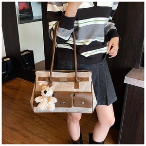 Detail of a marble-patterned tote bag with leather straps and a plush bear pendant
