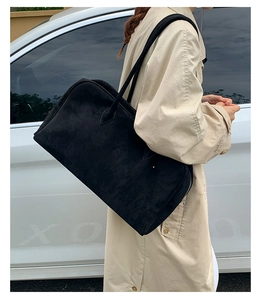 Foto exterior de un bolso Boston de ante negro al hombro para el trayecto diario otoñal