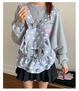 Detail of light blue polka dot backpack showing the ruffle trim and decorative strap buckles