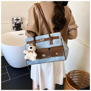 Detail view of denim tote bag with leather pockets and cute plush bear accessory
