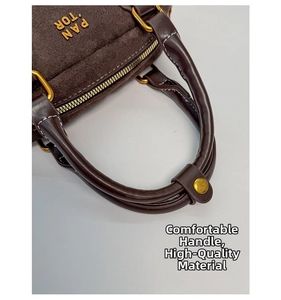Detalle del bolso Boston de gamuza marrón oscuro con asas de cuero y herrajes dorados