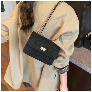 Side view of black quilted crossbody bag with gold turn-lock and chain strap on model