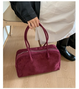 Detalle del bolso tote de ante burdeos con textura suave y asas largas en una modelo