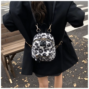Outdoor shot of a plush leopard print mini backpack with golden metal zippers and hardware