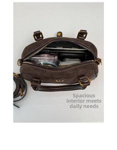 Interior espacioso del bolso Boston marrón oscuro con objetos diarios y piezas doradas
