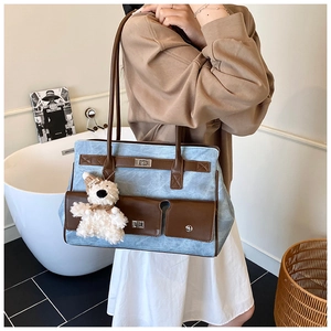Detail of vintage tote bag with light blue wash fabric and brown leather straps
