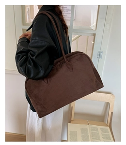 Detalle del bolso tote de ante marrón oscuro con acabado mate y correa larga de hombro