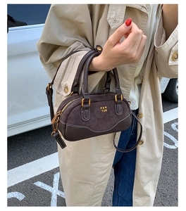 Primer plano detallado del mini bolso Boston de ante marrón oscuro con logo dorado PAN TOR