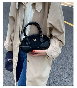 Primer plano de un bolso bandolera negro con logo dorado y textura mate en estilo callejero