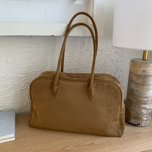 Sac fourre-tout Boston vintage en daim marron avec de longues anses sur une table