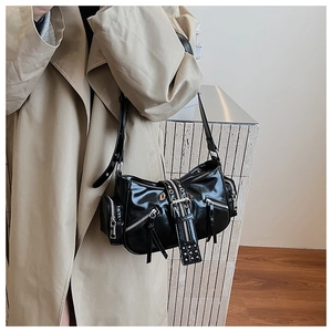 Detail of black glossy punk style bag with multi-zipper and buckle strap on trench coat