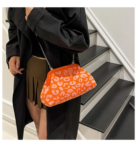 Detalle de bolso tipo concha de punto de leopardo rosa con borde naranja y cadena