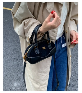 Vista de estilo callejero de un mini bolso Boston negro combinado con gabardina y vaqueros