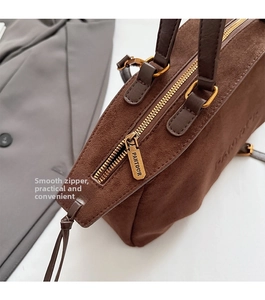Detail of golden zipper and embossed logo on brown suede leather shoulder bag
