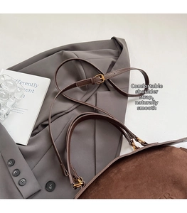 Detail of dark brown suede baguette bag with leather strap and vintage gold hardware