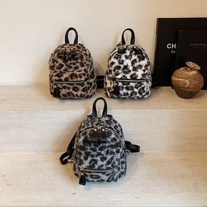 Three mini faux fur leopard print backpacks in assorted colors on display steps
