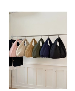 Row of colorful quilted cloud bags in six shades hanging on a metal display rack