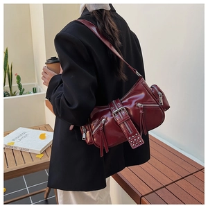 Detail of burgundy punk style shoulder bag with silver zippers and metal rivet hardware